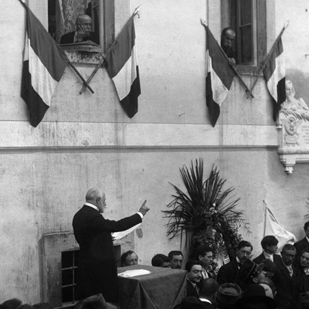 Oratore che si rivolge ad un uditorio, lapide in memoria di Enrico Ricci 1911